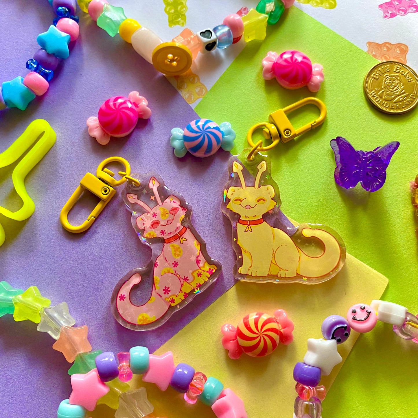 image features two cute keychains featuring original artwork by candy critters.
details in the background of the product photo contains bracelets, cute hair clips, charms, and an arcade token. (background items not included in purchase of keychain)
left keychain is the front side of the keychain, featuring an aisha (fictional online pet) painted the disco color.
right keychain is the back side, featuring an aisha painted the yellow color.
the hardware for this keychain is yellow.