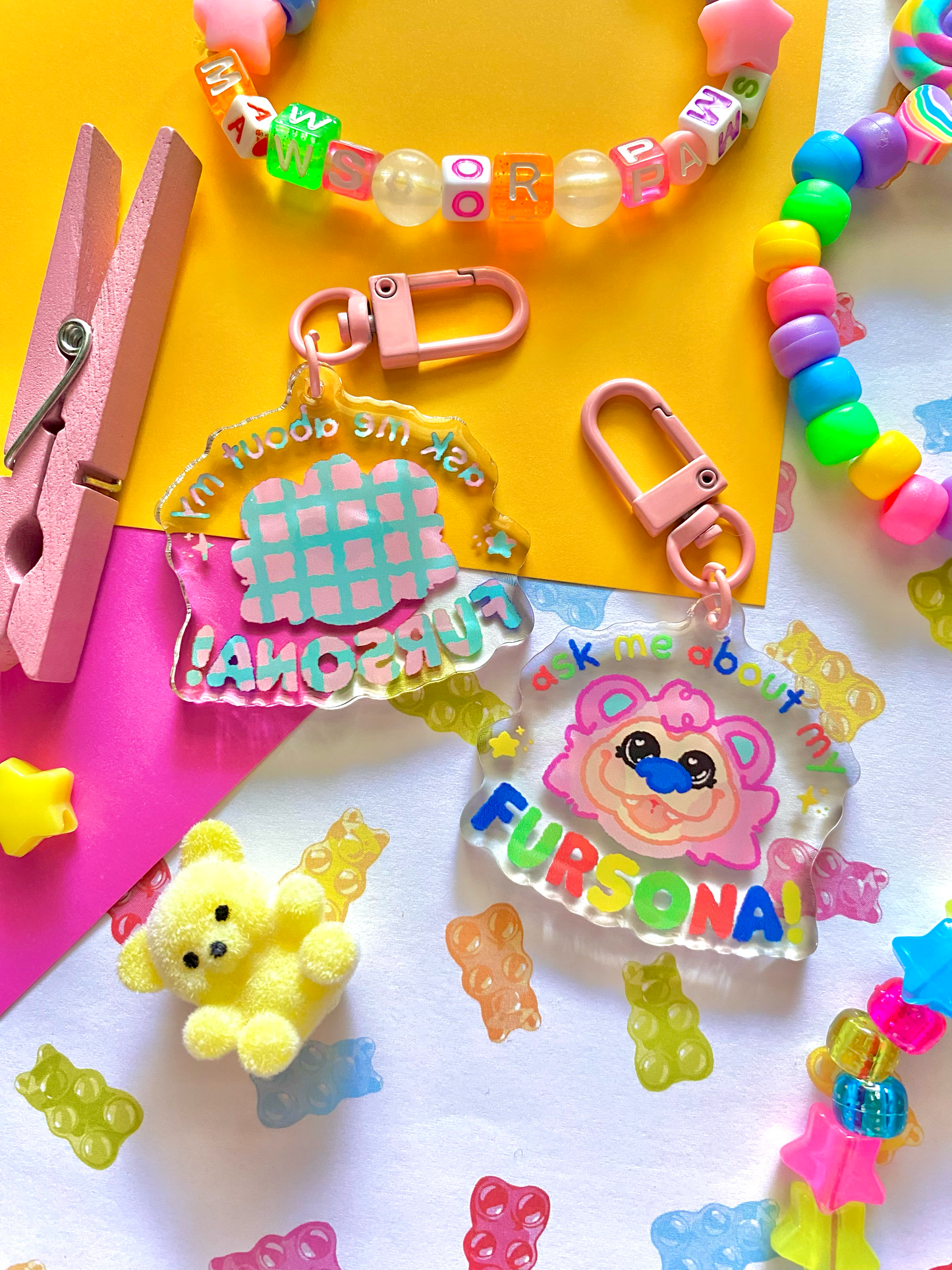 image features one keychains featuring original artwork by candy critters.
details in the background of the product photo contains cute printed paper, colorful kandi bracelets, a teddy bear charm, and a pink clothes pin. (background items not included in purchase of keychain)
keychain is double sided.
left side features a drawing of the silhouette of design.
right side features an image of a pink bear named caboose. surrounding text saying "ask me about my fursona"
hardware for keychain is pink