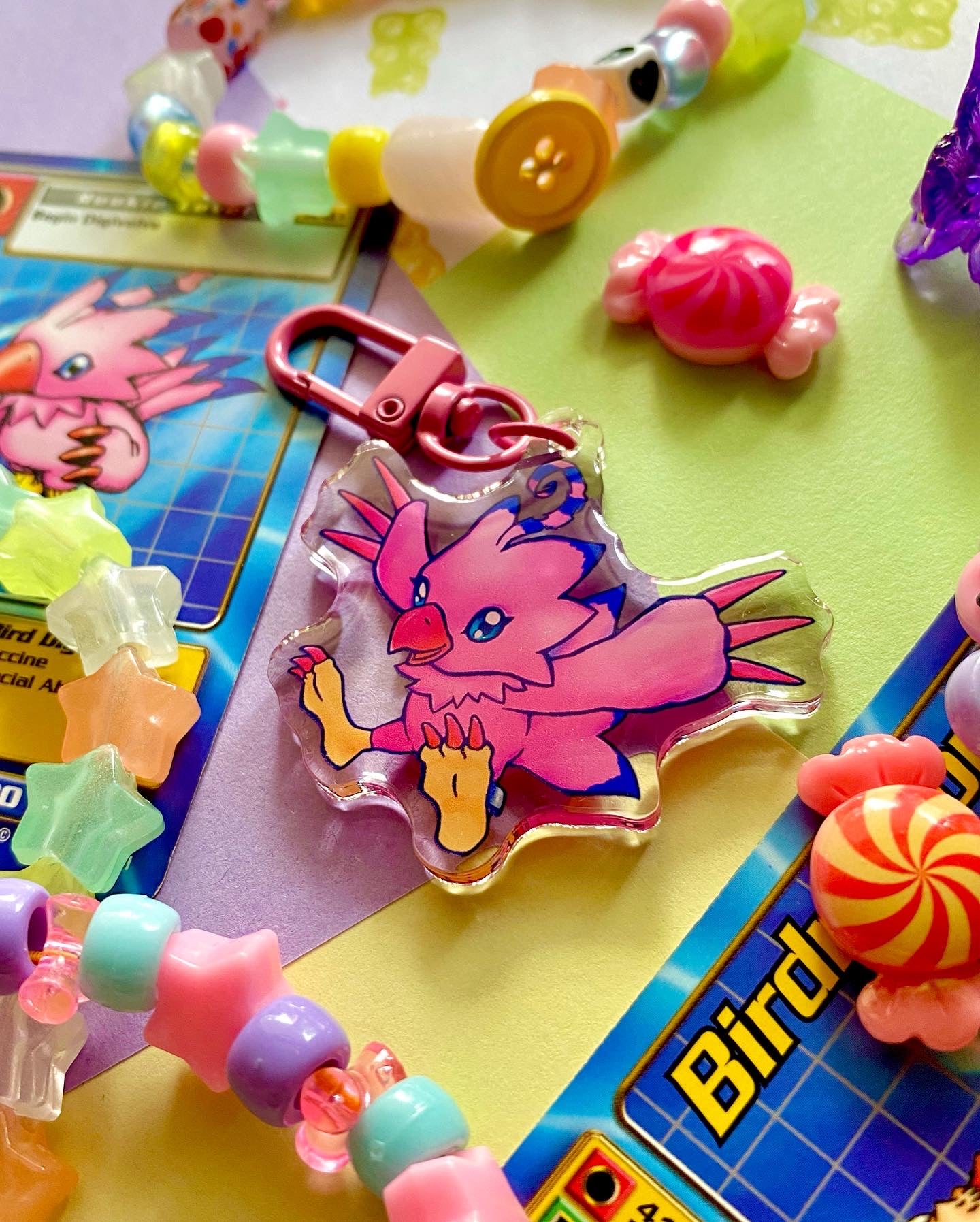 image features one keychain featuring original artwork by candy critters.
details in the background of the product photo contains a collage of trading cards, candy charms, and a kandi bracelets. (background items not included in purchase of keychain)
keychain is double sided with same design on both sides. features a drawing of a pink bird with her wings stretched out.
the hardware for this keychain is pink.