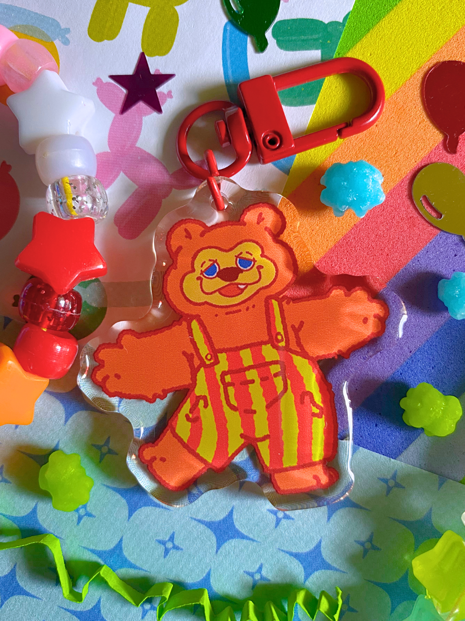 image features one keychains featuring original artwork by candy critters. 
details in the background of the product photo contains bracelets, confetti, cute paper, and konpeito candy pieces.. (background items not included in purchase of keychain)

 keychain is double sided with the same design on both sides. featuring a drawing of billy bob the bear with his arms outstretched, in a dancing pose. he is smiling.
the hardware for this keychain is red.